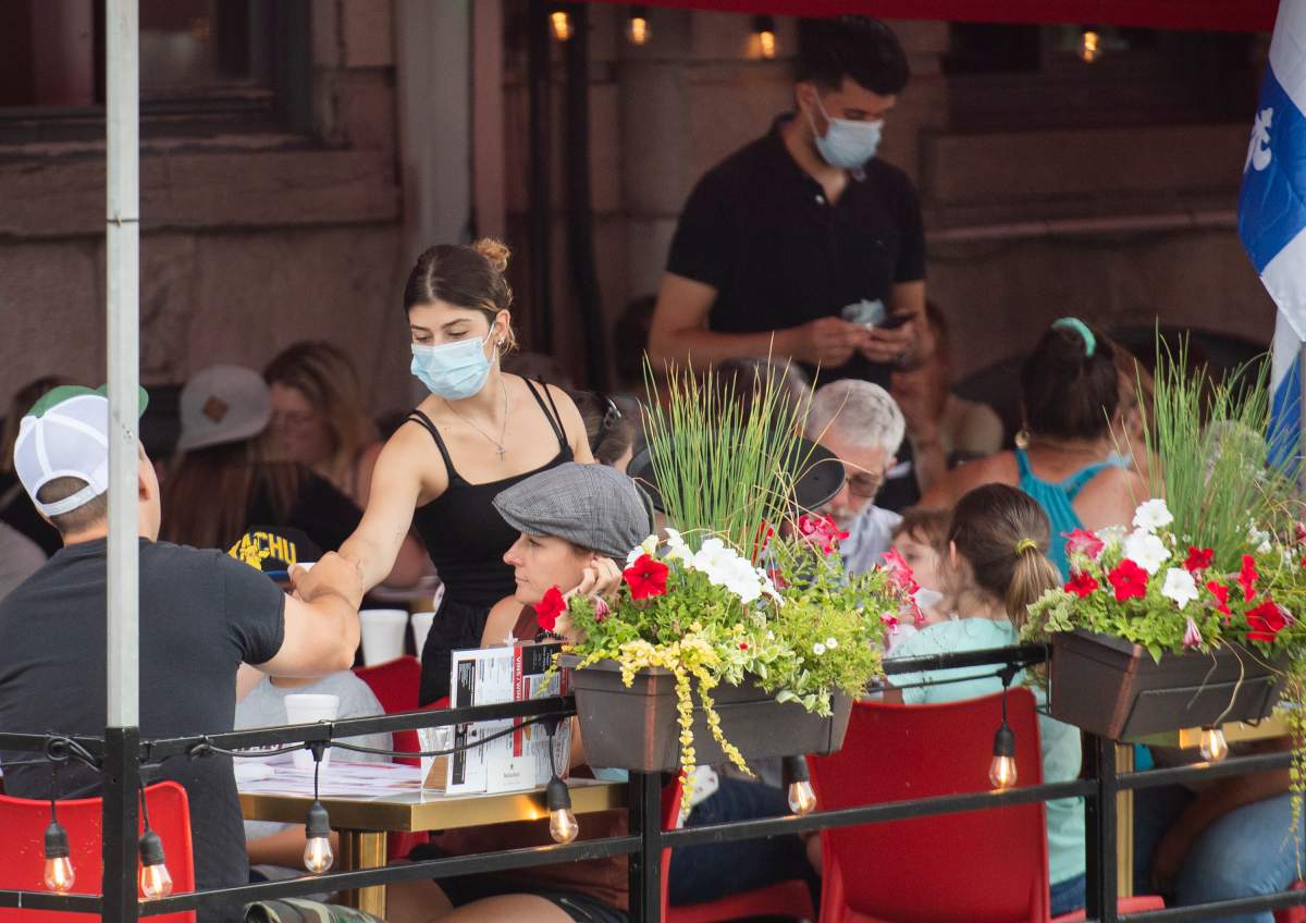 A server wears a face mask as she tends to customers in Old Montreal, Sunday, July 18 2021, as the COVID-19 pandemic continues in Canada and around the world.  