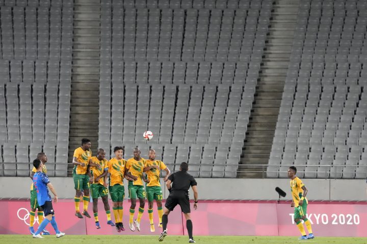 Japan’s Maya Yoshida, left, takes a penalty kick against South Africa as the stands sit empty during a men’s soccer match at the 2020 Summer Olympics, Thursday, July 22, 2021, in Tokyo, Japan.