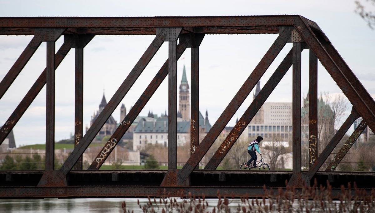 Parliament Hill is seen in the background as a person rides their bike across the Prince of Wales Bridge, in the midst of the COVID-19 pandemic on Sunday, May 17, 2020.