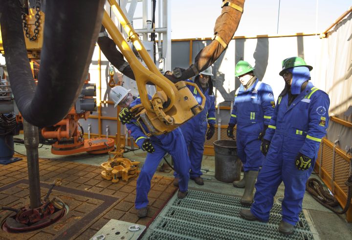 Senior Manager of field training and development, Ryan Morton, left, discusses procedure with trainees during a training session to lay down drill pipe on a rig floor at Precision Drilling in Nisku, Alta., on Friday, January 20, 2016. 