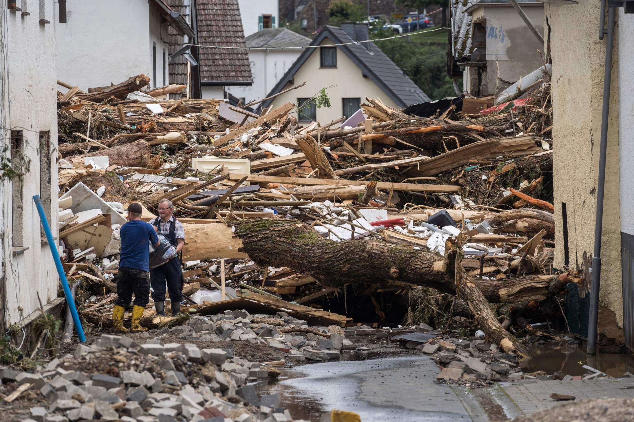 Two men try to remove goods from next to the debris of houses destroyed by the floods in Schuld.