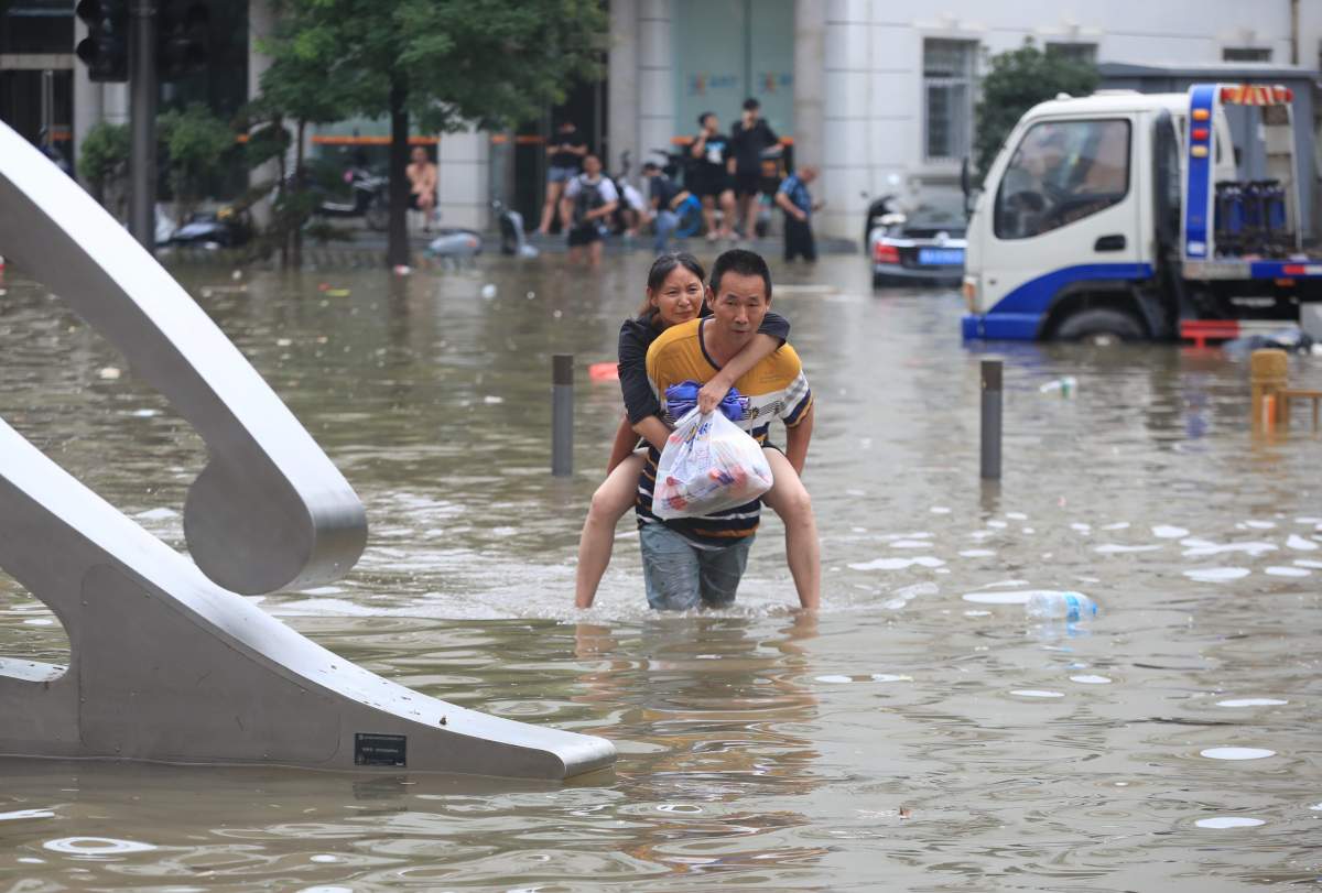 A man carries a woman in the flooded road after record downpours receded in Zhengzhou city in central China’s Henan province Wednesday, July 21, 2021.