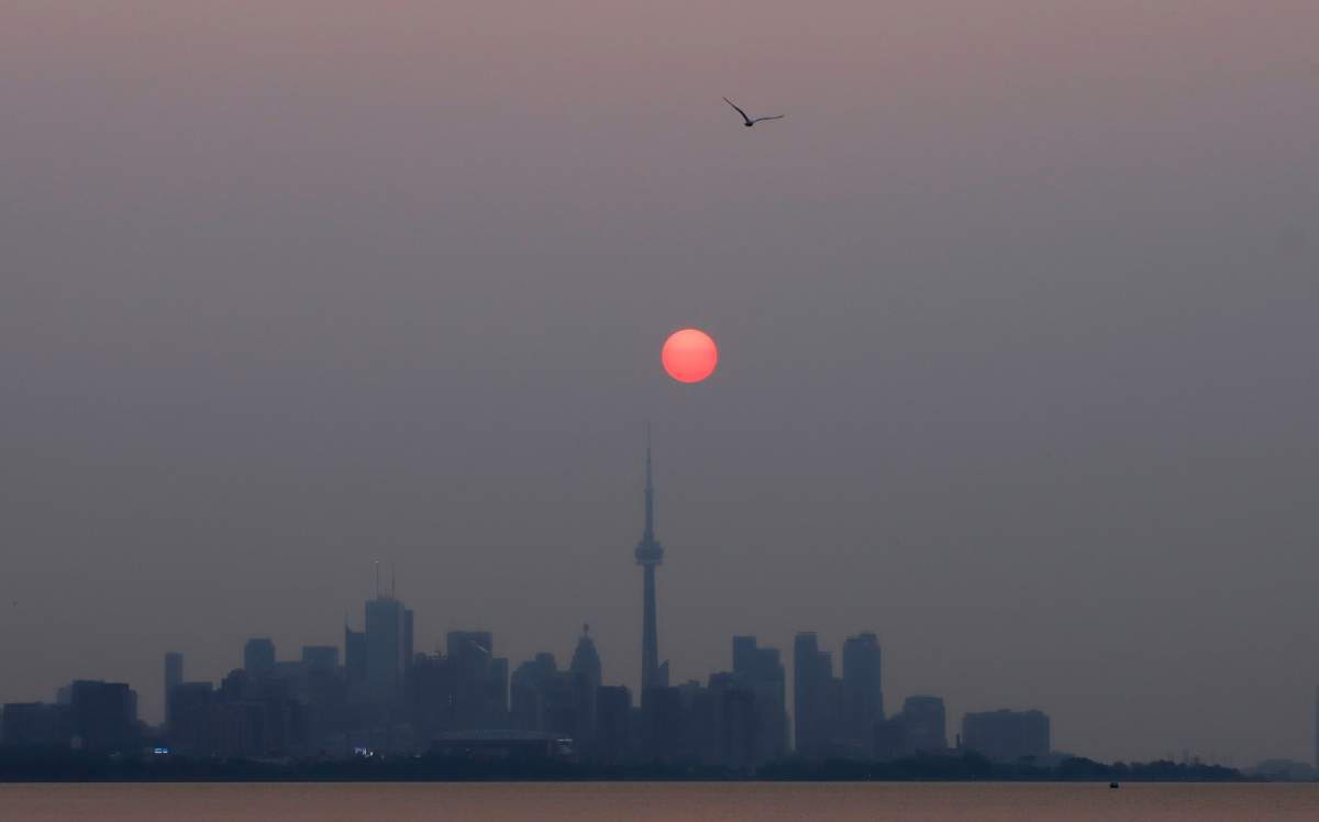 The sun rises above the CN Tower through a thick haze caused by smoke from forest fires burning in Western Canada moving through the upper atmosphere on July 19, 2021 in Toronto, Canada.