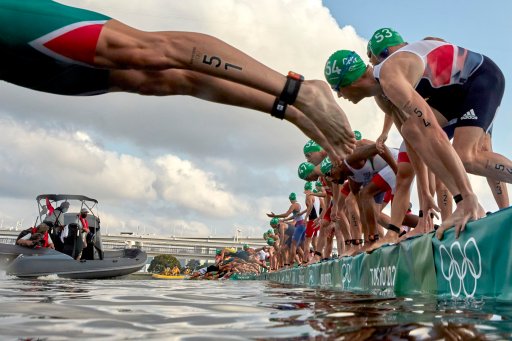 TOKYO, JAPAN – JULY 26: Triathletes dive into the water as a broadcast boat prevents all swimmers from starting forcing a restart before the Men’s Individual Triathlon on day three of the Tokyo 2020 Olympic Games at Odaiba Marine Park on July 26, 2021 in Tokyo, Japan.