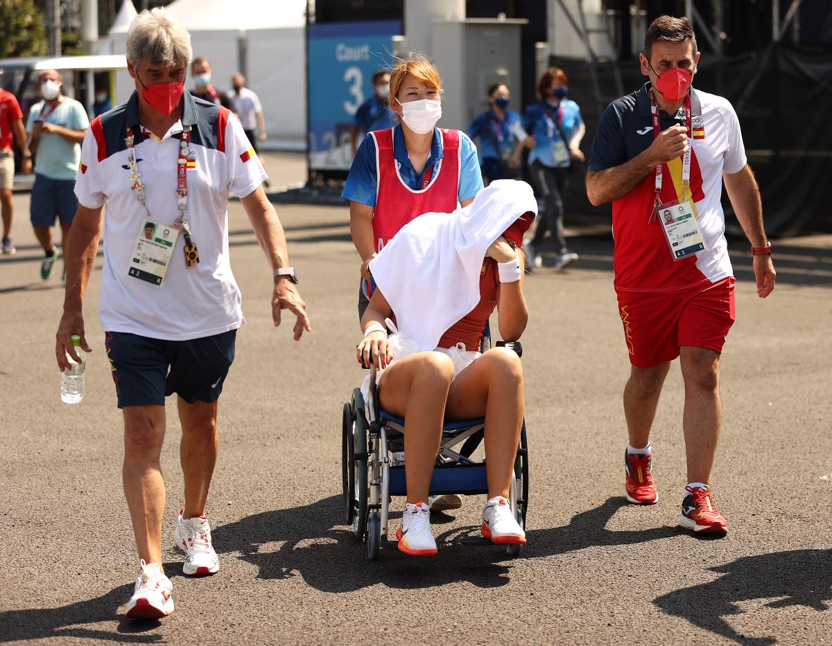 Paula Badosa of Team Spain is helped away from the court in a wheelchair after having to retire due to heatstroke from her Women’s Singles Quarterfinal match against Marketa Vondrousova of Team Czech Republic on day five of the Tokyo 2020 Olympic Games at Ariake Tennis Park on July 28, 2021 in Tokyo, Japan.
