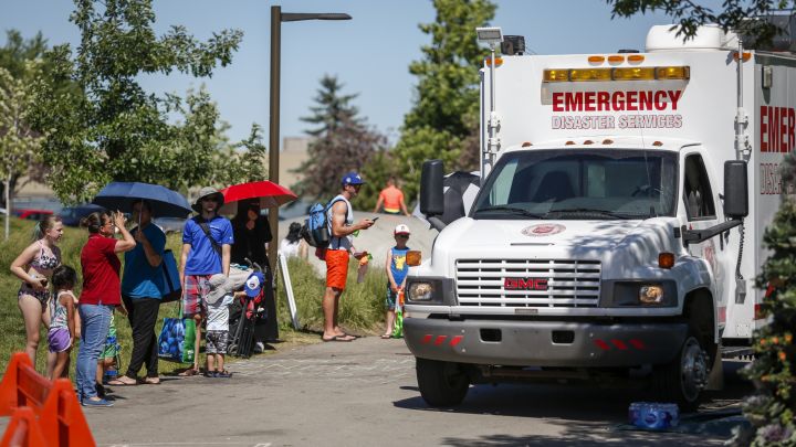 A Salvation Army EMS vehicle is setup as a cooling station as people lineup to get into a splash park while trying to beat the heat in Calgary, Alta., Wednesday, June 30, 2021.