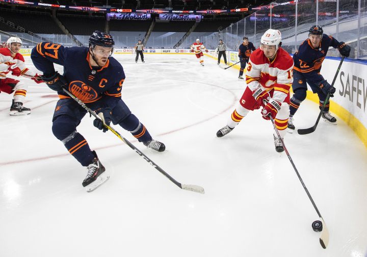 Edmonton Oilers' Connor McDavid (97) and Calgary Flames' Johnny Gaudreau (13) battle for the puck during first period NHL action in Edmonton on Saturday, May 1, 2021.