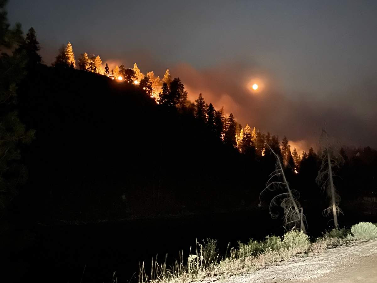 The Nk’Mip Creek wildfire burns down the hillside southeast of Oliver, B.C., threatening homes along Shrike Hill Road on Wednesday evening, July 21, 2021.