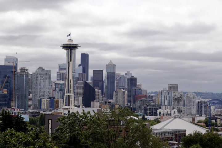 A flag with the new logo for the newly-named Seattle NHL hockey team, the Seattle Kraken, flies atop the iconic Space Needle and in view of the team's arena, lower right, Thursday, July 23, 2020, in Seattle. 