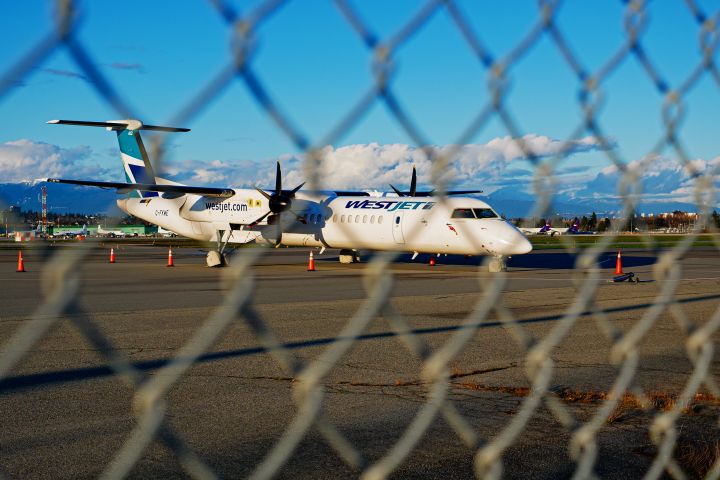 A WestJet Encore DeHavilland Canada Dash 8-400 turboprop regional airliner (C-FKWE) parked and stored at the south terminal of Vancouver International Airport, Richmond, B.C. on Monday, March 22, 2021. 
