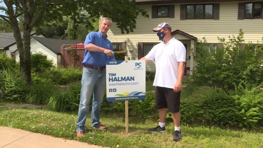 PC Leader Tim Houston and Dartmouth East candidate Tim Halman put up a lawn sign.