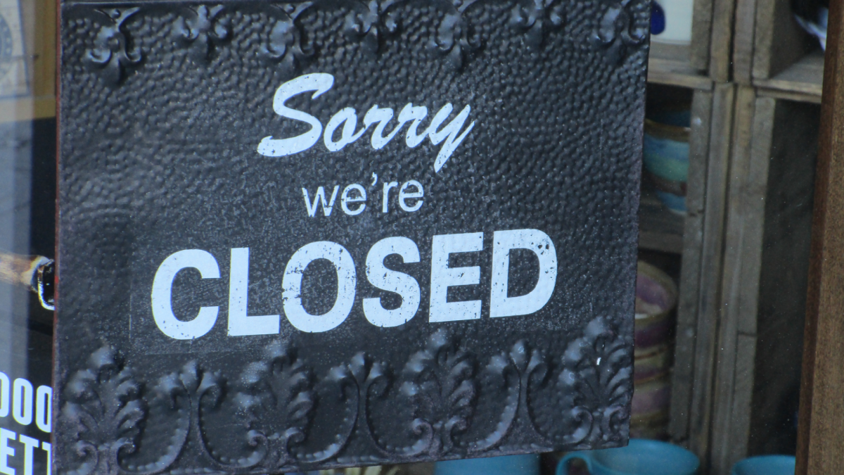 'Sorry, we're closed' sign is displayed in a store window.
