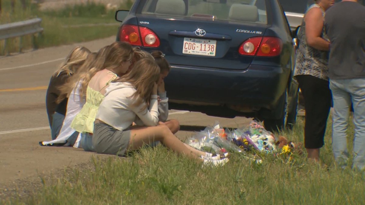 Mourners grieve at a roadside memorial where two Sprinbank teens were killed in a single-vehicle crash July 15, 2021.