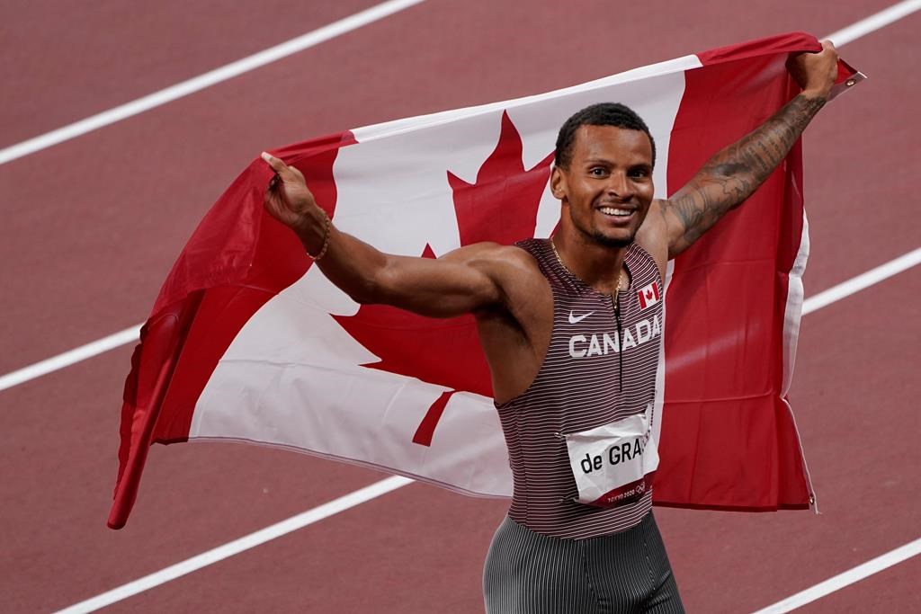 Canada's Andre De Grasse celebrates with the Canadian flag after racing to a gold medal in the Men's 200m final during the Tokyo Olympics in Tokyo, Japan on Wednesday, August 4, 2021.
