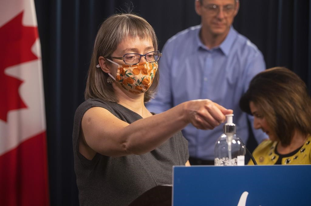 Dr. Deena Hinshaw, Alberta's chief medical officer of health, sanitizes her hands before providing an update on COVID-19 and back-to-school guidance in Edmonton on Friday, Aug. 13, 2021. Alberta recorded its highest single-day increase in COVID-19 cases in almost three months on Wednesday with 678 new infections. THE CANADIAN PRESS/Jason Franson.
