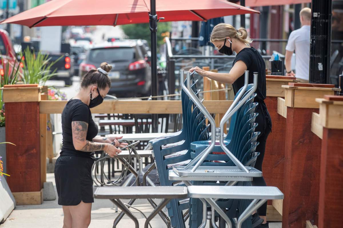 Wait staff wear masks to protect them from the COVID-19 virus while setting up a patio in Kingston, Ontario on Wednesday August 11, 2021. THE CANADIAN PRESS IMAGES/Lars Hagberg.