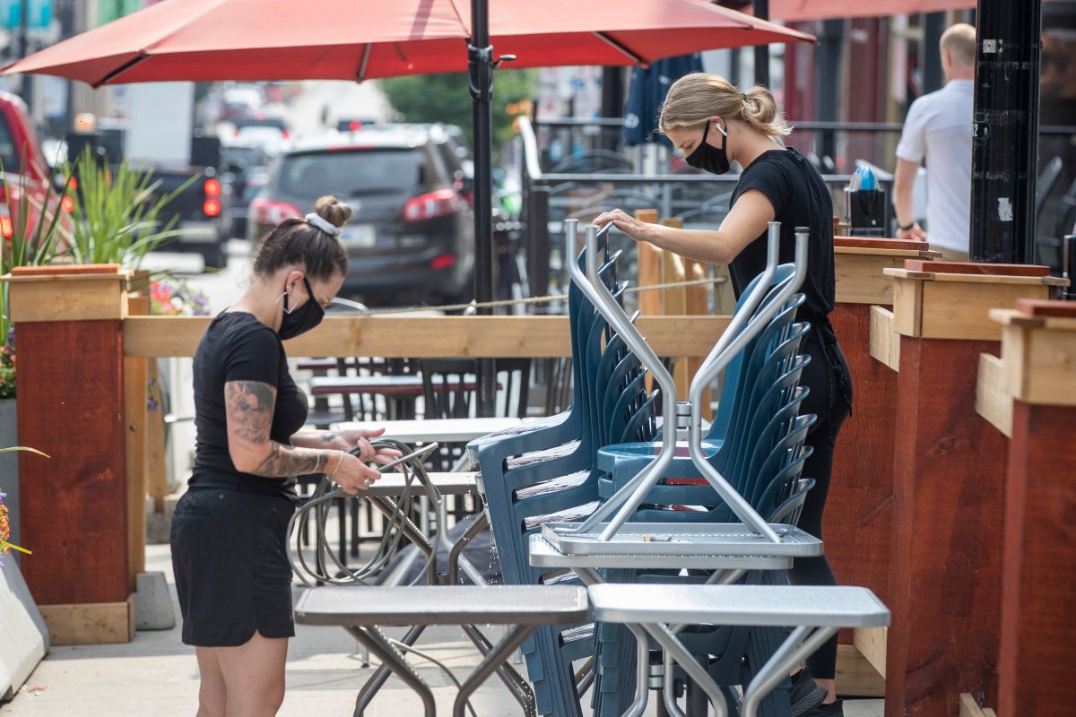 Wait staff wear masks to protect them from the COVID-19 virus while setting up a patio in Kingston, Ontario on Wednesday August 11, 2021. THE CANADIAN PRESS IMAGES/Lars Hagberg.