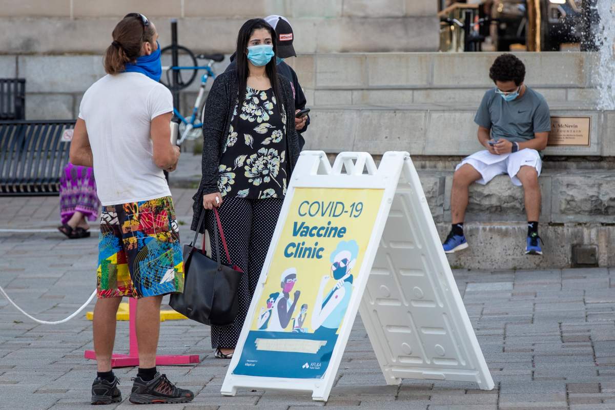 People wear masks as they wait at a COVID-19 walk-in vaccine clinic in Kingston, Ont., on Thursday, Aug. 12, 2021.