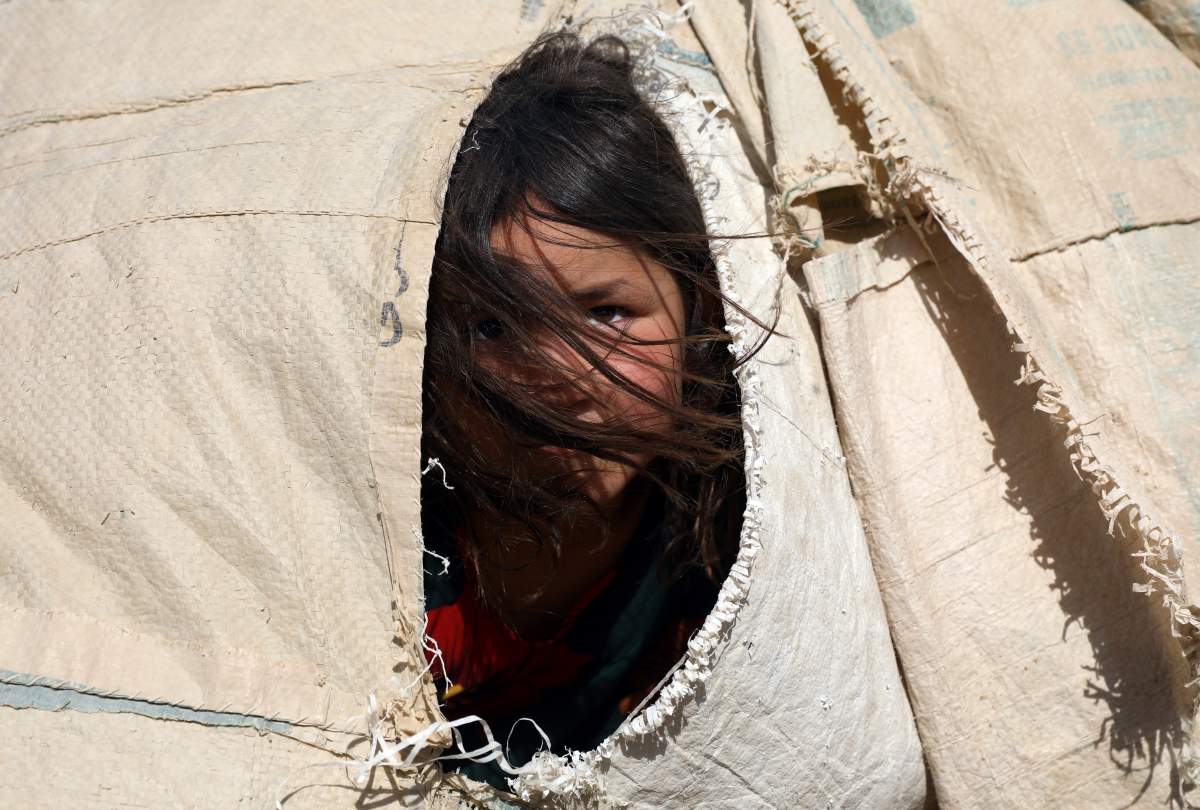 An internally displaced Afghan girl who fled her home due to fighting between the Taliban and Afghan security personnel, peers from her makeshift tent at a camp on the outskirts of Mazar-e-Sharif, northern Afghanistan, Thursday, July 8, 2021. (AP Photo/Rahmat Gul)