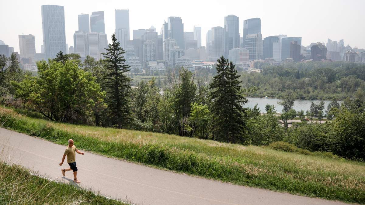 A haze of wildfire smoke from B.C. hangs over downtown as a person walks in Calgary, Alta., Thursday, July 15, 2021.