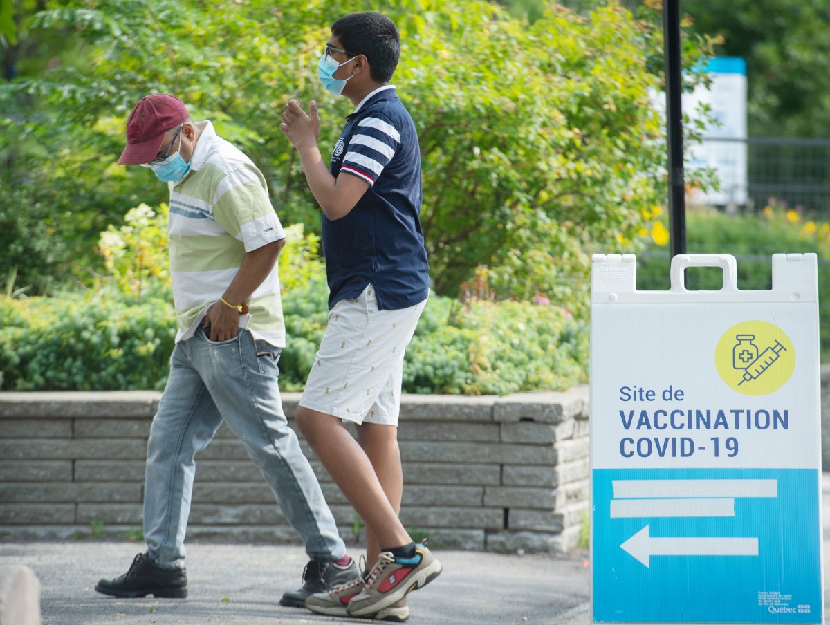 People walk by a COVID-19 vaccination sign in Montreal, Saturday, August 7, 2021, as the COVID-19 pandemic continues in Canada and around the world. 