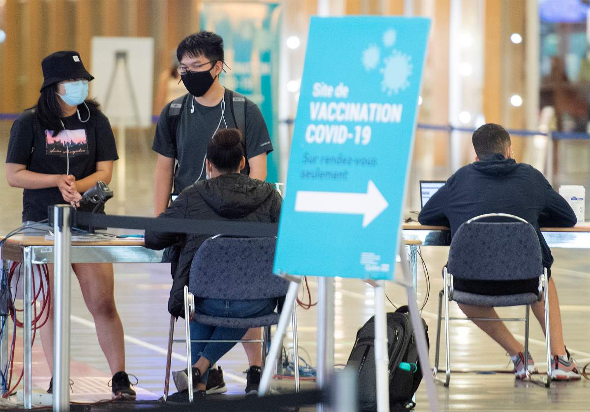 People are shown at a COVID-19 vaccination site in Montreal, Sunday, August 8, 2021, as the COVID-19 pandemic continues in Canada and around the world. THE CANADIAN PRESS/Graham Hughes.