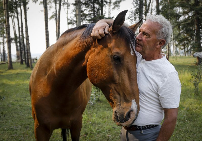 Horse trainer Ian Tipton hugs horse Falco Amadeus, father of Jacinto, near the place where horses Jacinto and Mowgli were killed by lightning at his facility near Sundre, Alta., Thursday, Aug. 5, 2021.