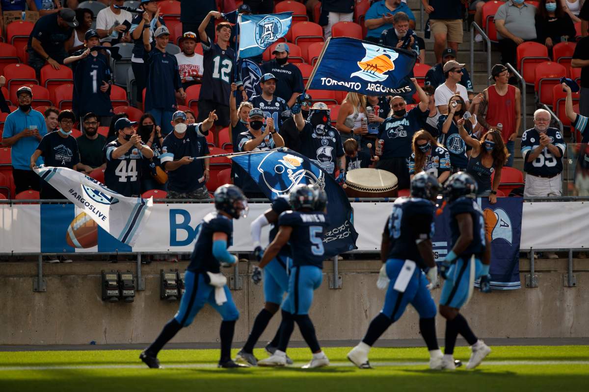 Fans celebrate with the team as Toronto Argonauts players score a touchdown during first half CFL football action against the Winnipeg Blue Bombers, in Toronto, Saturday, Aug. 21, 2021.