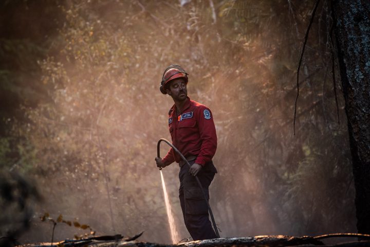 FILE. Wildland firefighter Sasha Terhoch sprays water on hot spots remaining from a controlled burn the B.C. Wildfire Service conducted to help contain the White Rock Lake wildfire on Okanagan Indian Band land, northwest of Vernon, B.C., on Wednesday, Aug. 25, 2021.