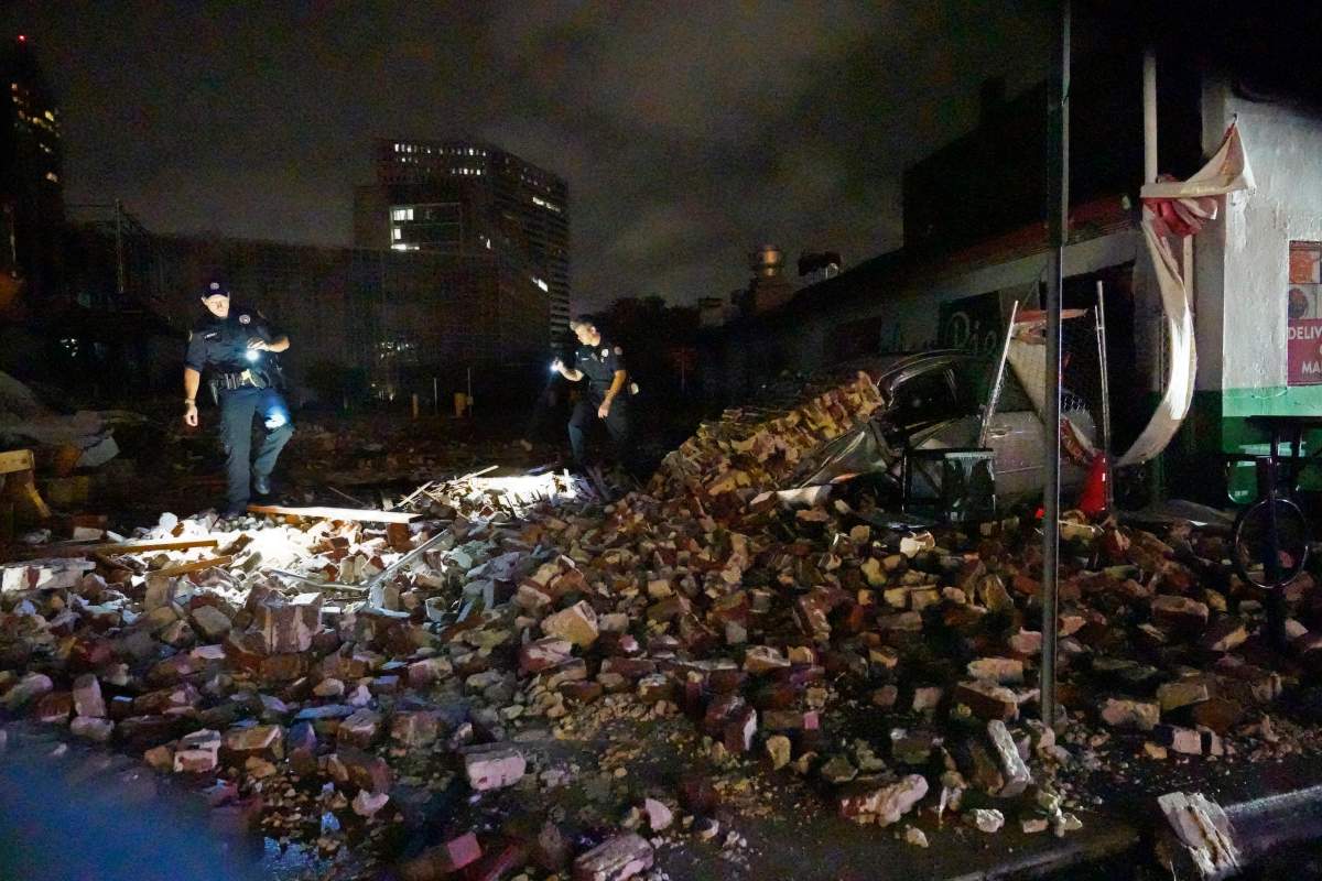 New Orleans Police detectives Adam Buckner, left, and Alexander Reiter, look over debris from a building that collapsed during Hurricane Ida in New Orleans, Monday, Aug. 30, 2021. (AP Photo/Gerald Herbert)