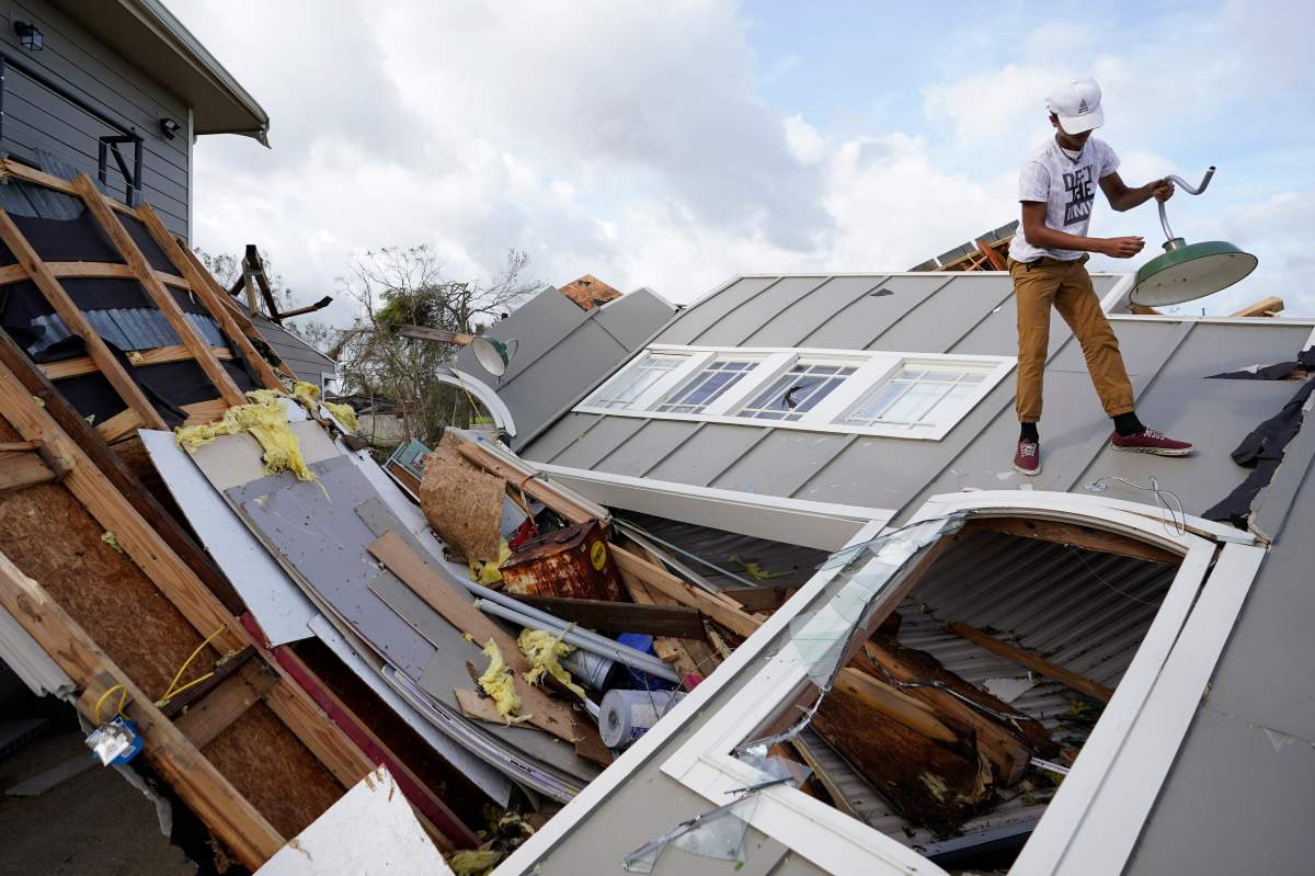 Jeremy Hodges removes a light from his family’s destroyed storage unit in the aftermath of Hurricane Ida, Monday, Aug. 30, 2021, in Houma, La. (AP Photo/David J. Phillip)