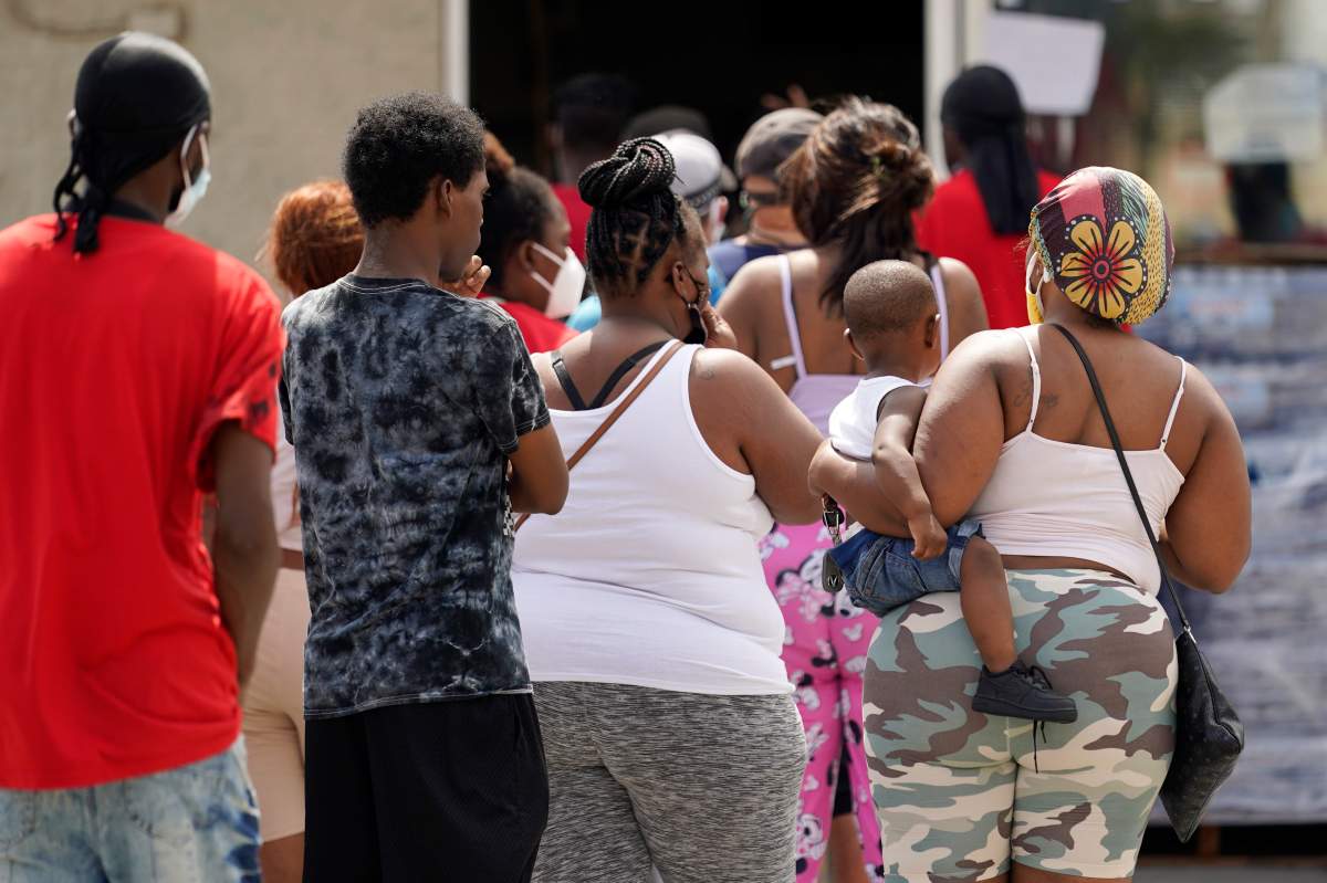 Customers stand in line to enter a convenience store that opened without electricity after the effects the effects of Hurricane Ida knocked out power in the area, Monday, Aug. 30, 2021, in Nhew Orleans, La. (AP Photo/Eric Gay)