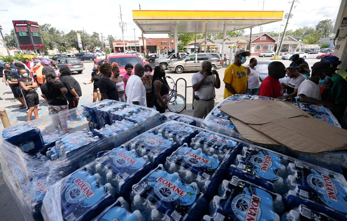 Customers stand in line to shop at a convenience store with no electricity after the effects the effects of Hurricane Ida knocked out power in the area, Monday, Aug. 30, 2021, in Nhew Orleans, La. (AP Photo/Eric Gay)