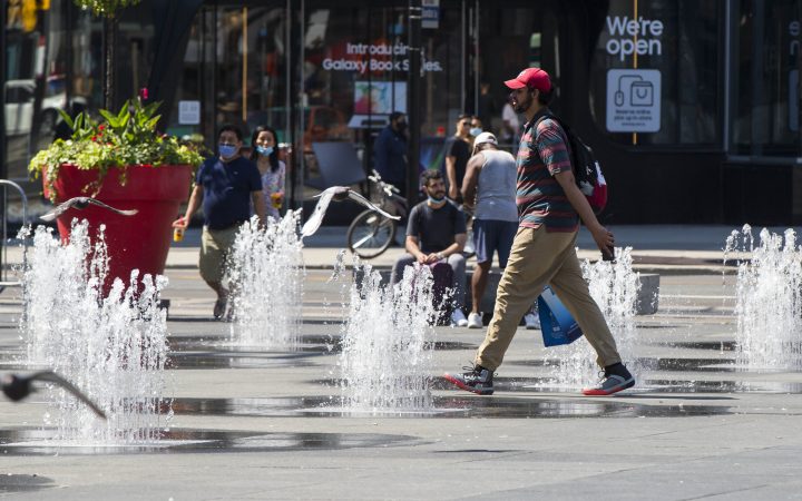 A man walks through fountains in Yonge-Dundas Square in Toronto on Aug. 23, 2020.