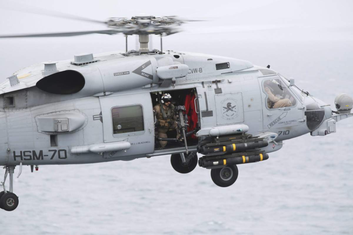 FILE -- In this Tuesday, March 21, 2017 photograph, an MH-60 helicopter lands on the USS George H.W. Bush as it travels through the Strait of Hormuz. (AP Photo/Jon Gambrell).