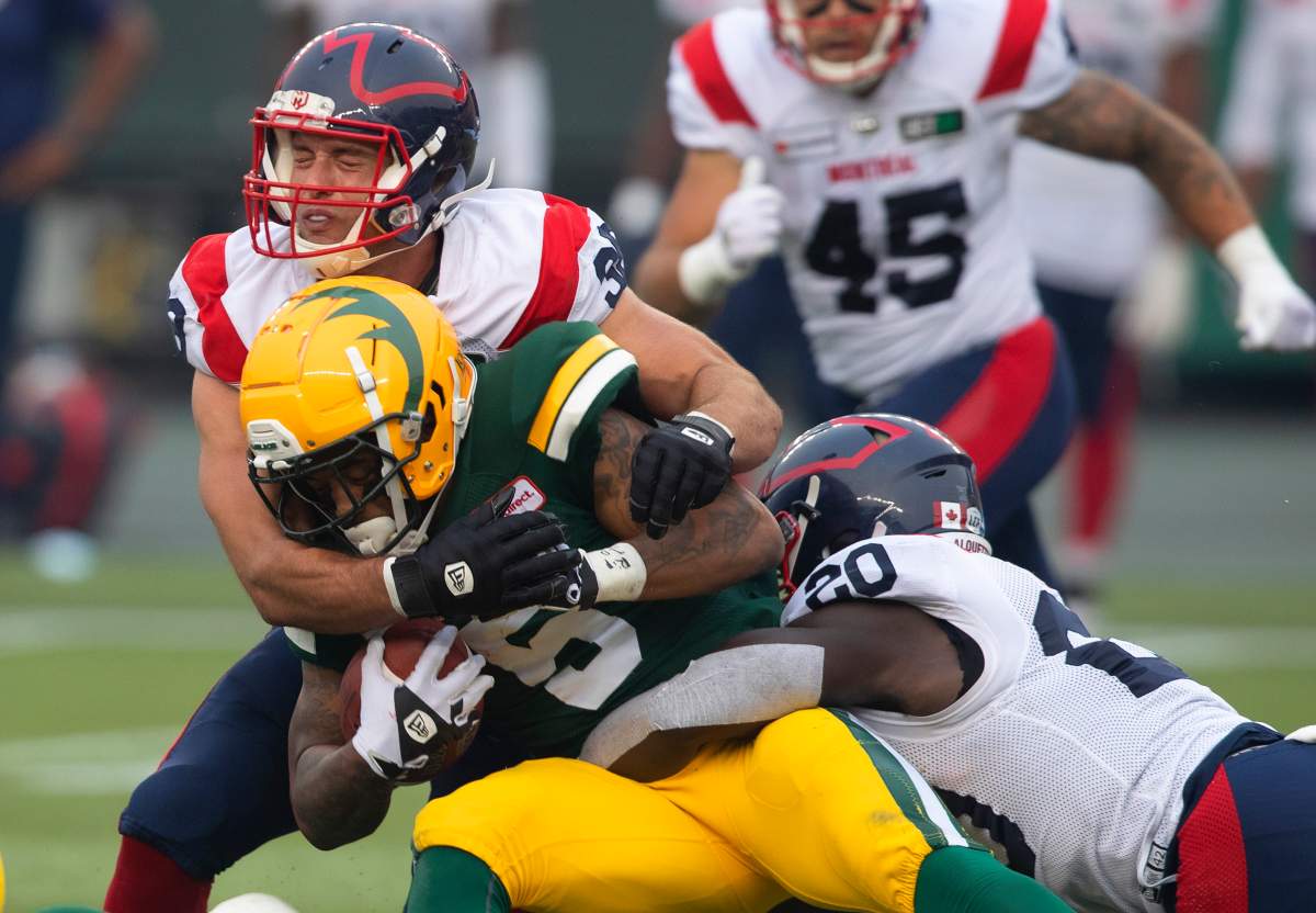 Montreal Alouettes' Christophe Normand (38) and Jeshrun Antwi (20) tackle Edmonton Elks' Terry Williams (5) during second half CFL action in Edmonton, Alta., on Saturday August 14, 2021.