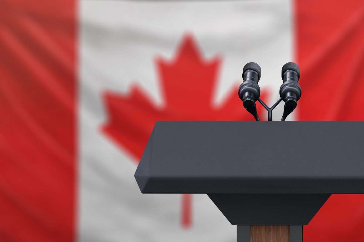 Podium lectern with two microphones and Canadian flag in background.