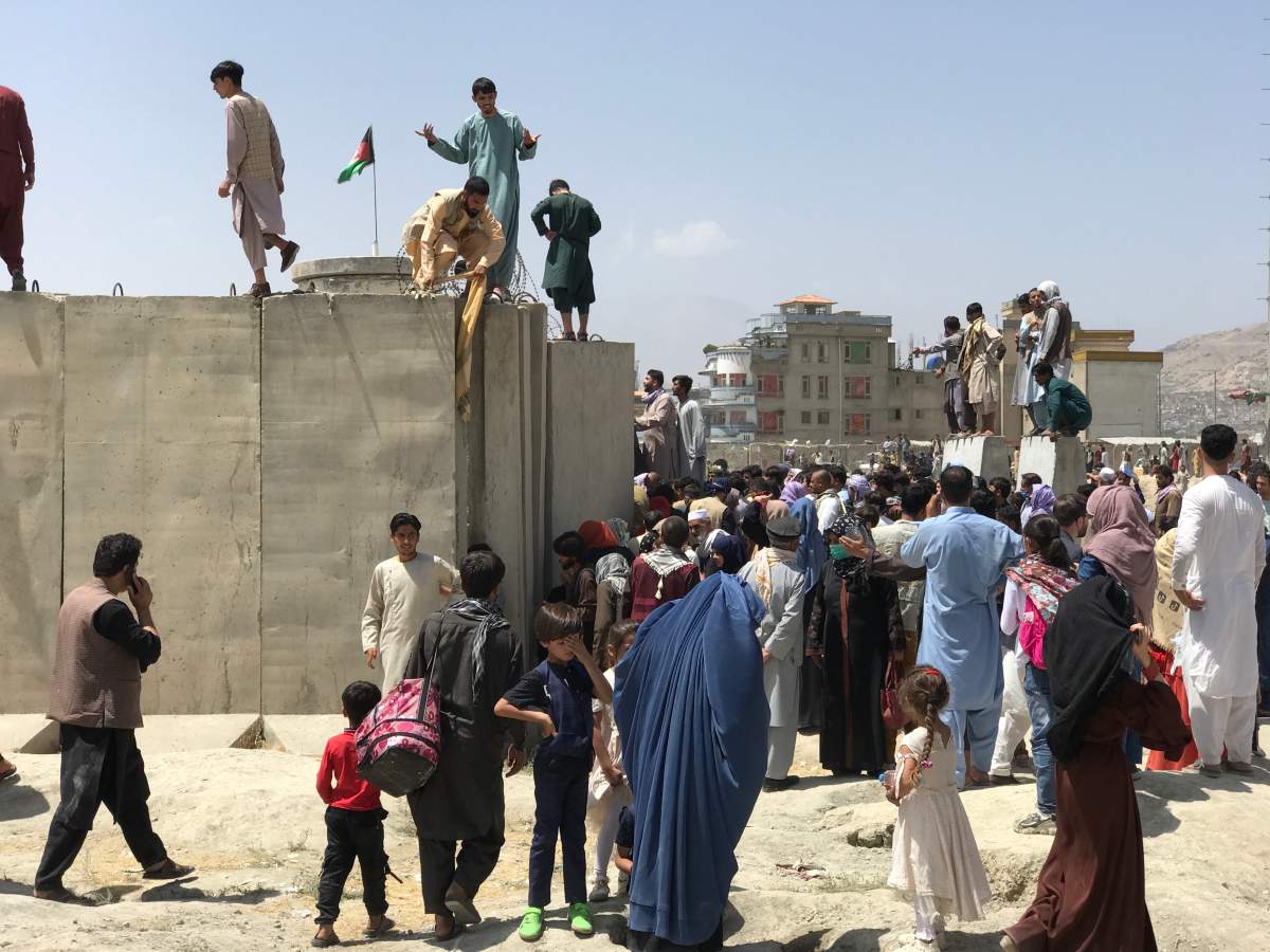 People struggle to cross the boundary wall of Hamid Karzai International Airport to flee the country after rumors that foreign countries are evacuating people even without visas, after the Taliban over run of Kabul, Afghanistan on Aug. 16, 2021.