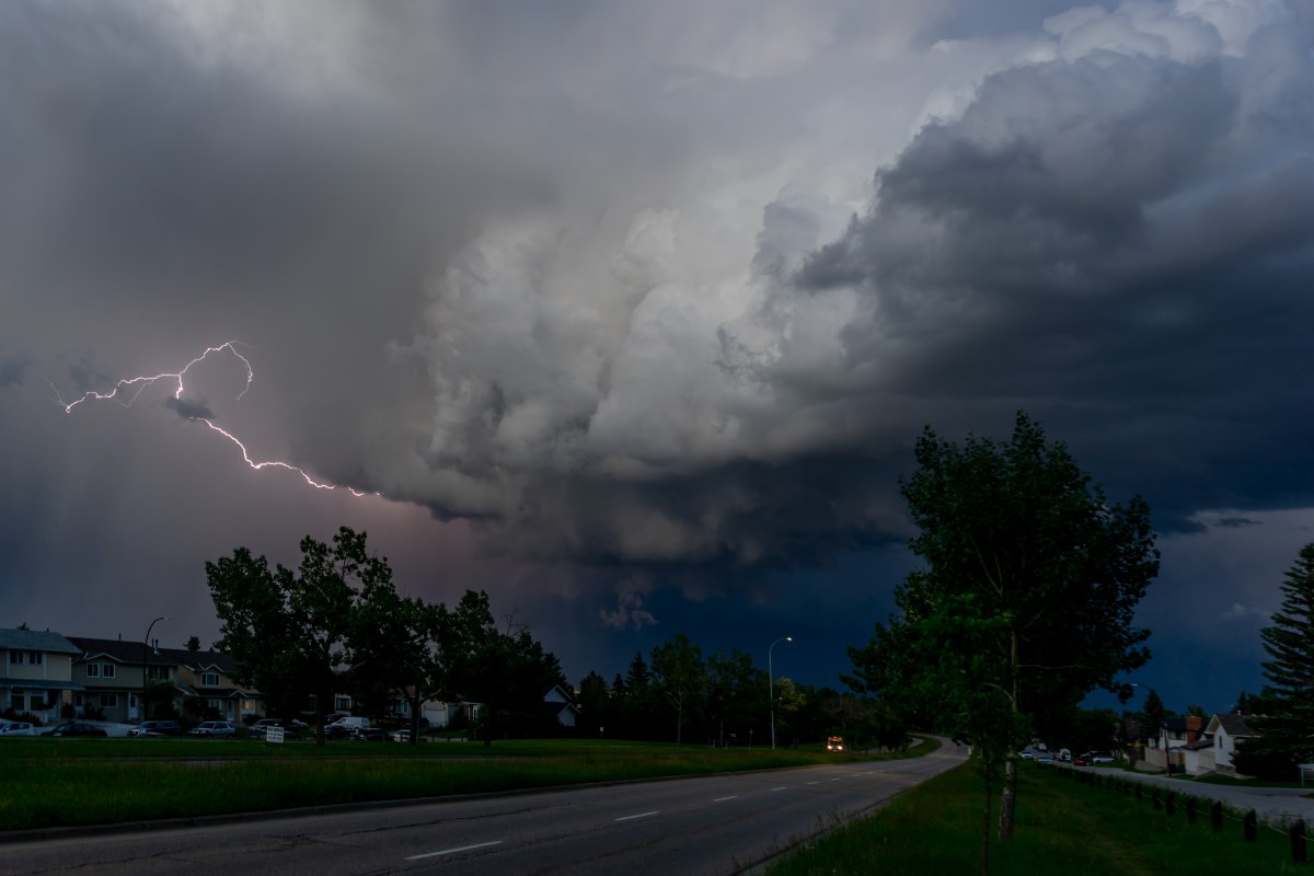 A bolt of lightning comes from a storm cloud above a residential area of Calgary, Alta.