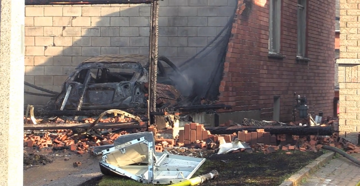 A burned-out car is seen in the garage of the home.