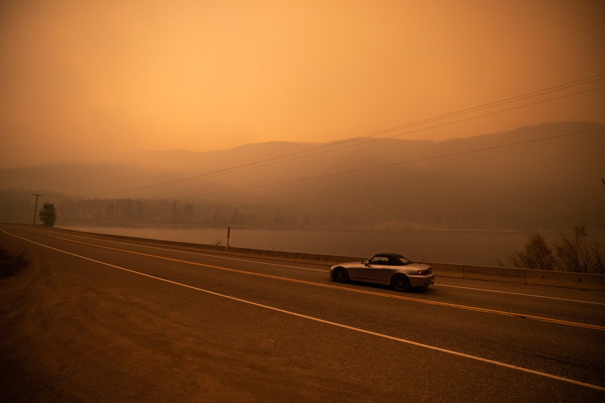 Thick smoke from the White Rock Lake wildfire fills the air and nearly blocks out the sun just after 3 p.m. as a motorist travels on Highway 97 in Monte Lake, east of Kamloops, B.C., on Saturday, August 14, 2021.