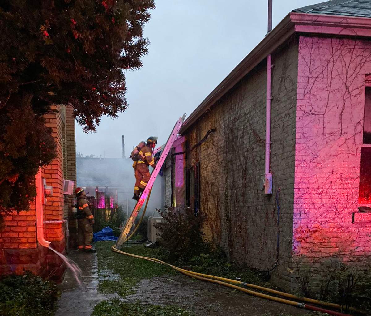 A London Fire Department member climbs a ladder to access the roof of 231 Waterloo St. as smoke comes from the rear of the property, Sept, 22, 2021.