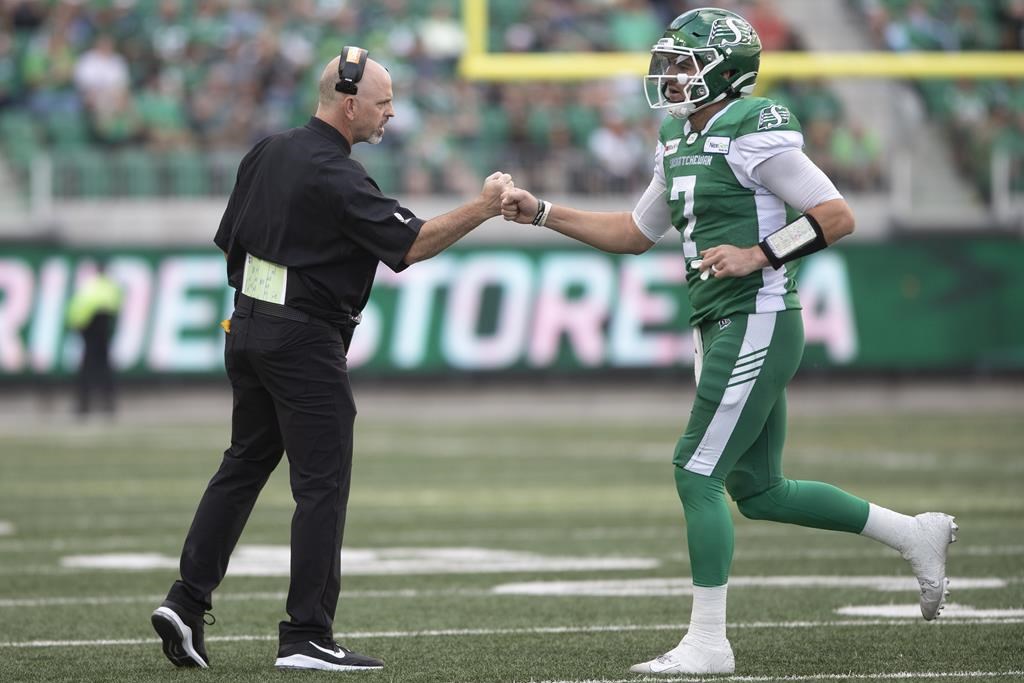 Saskatchewan Roughriders head coach Craig Dickenson bumps fists with quarterback Cody Fajardo (7) during first half CFL football action against the Ottawa Redblacks in Regina on Saturday, August 21, 2021. THE CANADIAN PRESS/Kayle Neis.