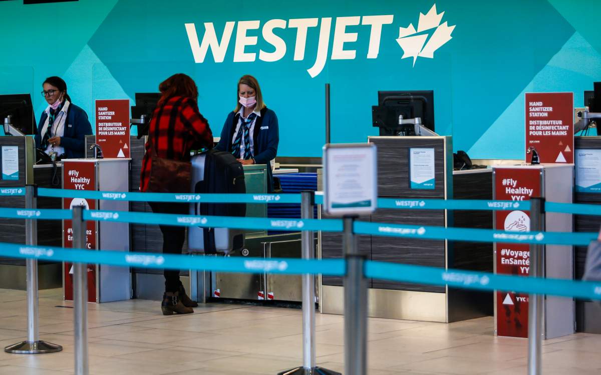 A passenger checks in at a Westjet counter at  the Calgary Airport in Calgary, Alta., Friday, Oct. 30, 2020, amid a worldwide COVID-19 pandemic. 