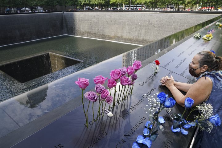 FILE - In this Friday Sept. 11, 2020, file photo, a mourner prays over the etched name of the deceased Emilio Pete Ortiz at the National September 11 Memorial and Museum in New York. Authorities say a U.S. Army soldier has been arrested in Georgia on terrorism charges after he spoke online about plotting to blow up the 9/11 Memorial in New York City and attack U.S. soldiers in the Middle East. 