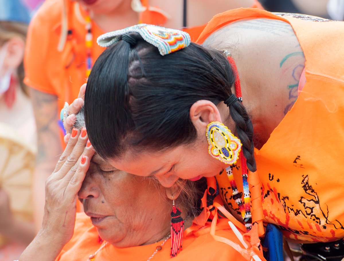 A woman is consoled during a gathering and march to honour Indigenous children, denounce genocide and demand justice for residential school victims in Montreal, Thursday, July 1, 2021.