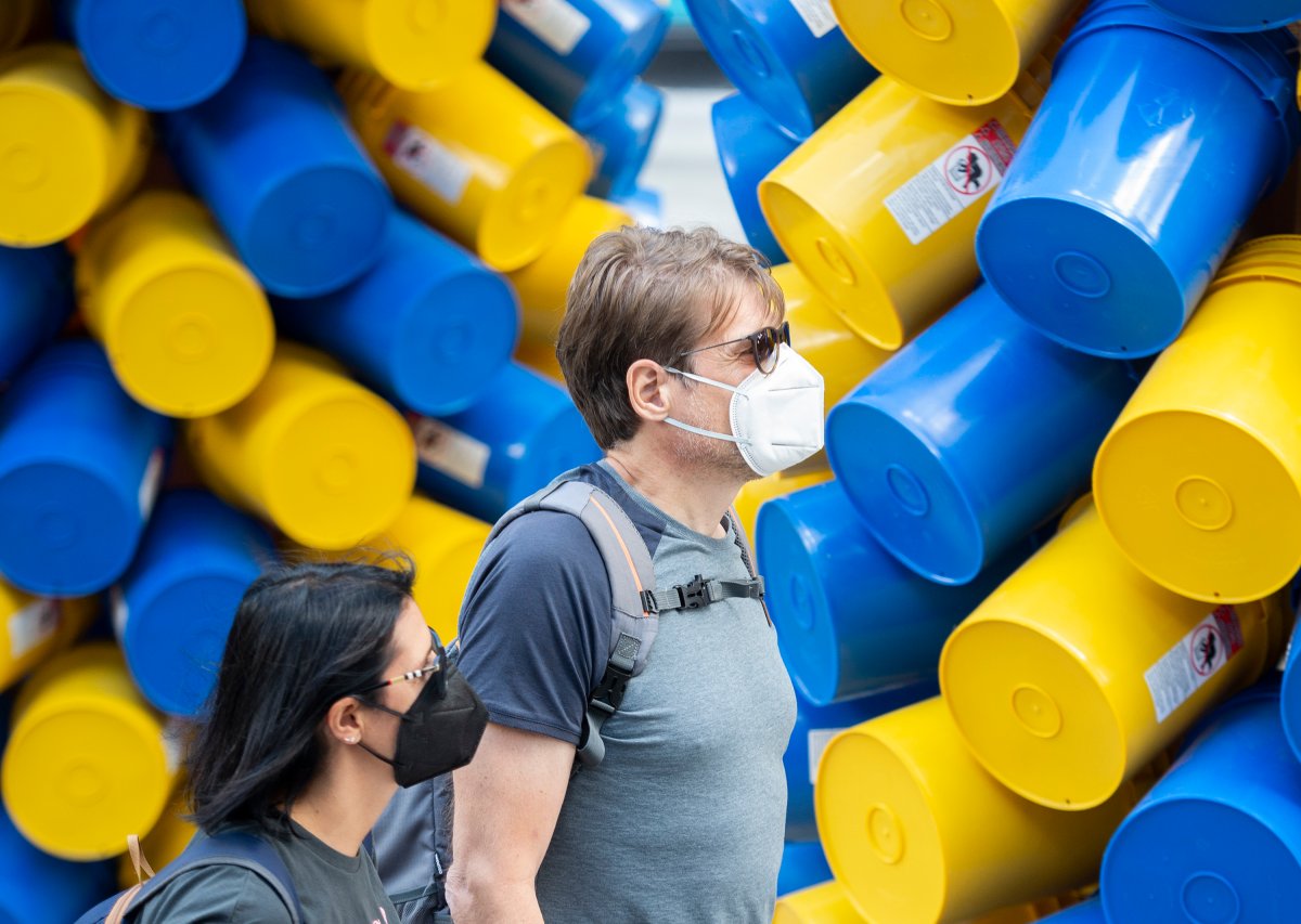 People wear face masks as they walk by an art installation in Montreal, Saturday, July 31, 2021, as the COVID-19 pandemic continues in Canada and around the world. 