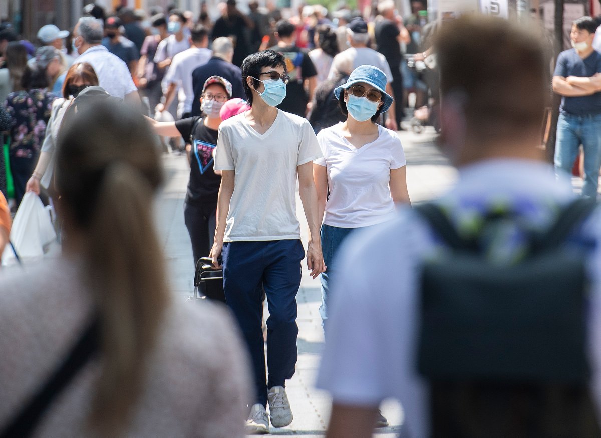 People wear face masks as they walk along a street in Montreal, Sunday, August 8, 2021, as the COVID-19 pandemic continues in Canada and around the world. 