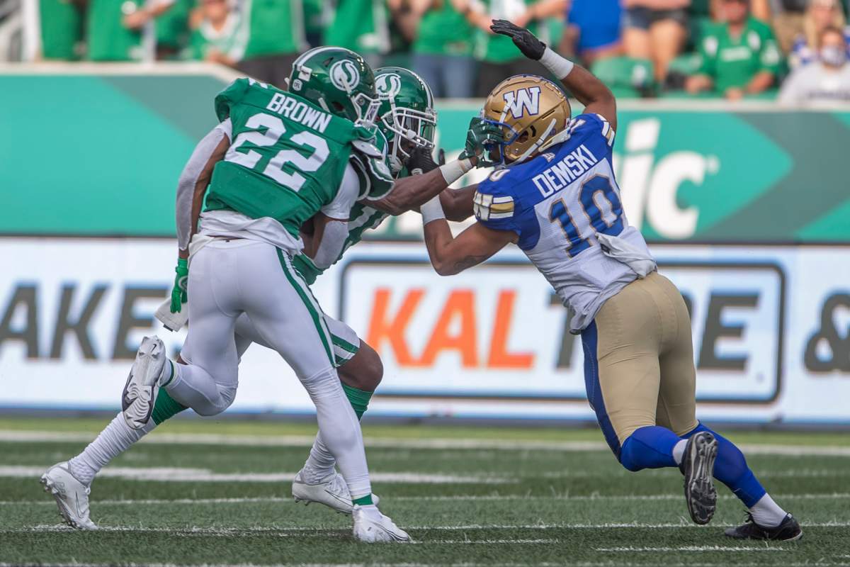 Saskatchewan Roughriders safety Mike Edem (15) and Winnipeg Blue Bombers wide receiver Nic Demski (10) clash during first half CFL football action in Regina, Sunday, Sept. 5, 2021.