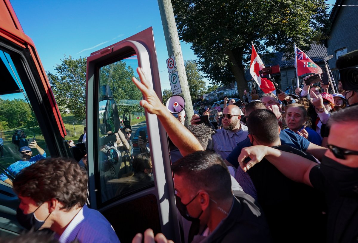 RCMP security detail put their hands up to protect Liberal Leader Justin Trudeau from rocks as protesters shout and throw gravel while leaving a campaign stop at a local microbrewery during the Canadian federal election campaign in London Ont., on Monday, Sept. 6, 2021.